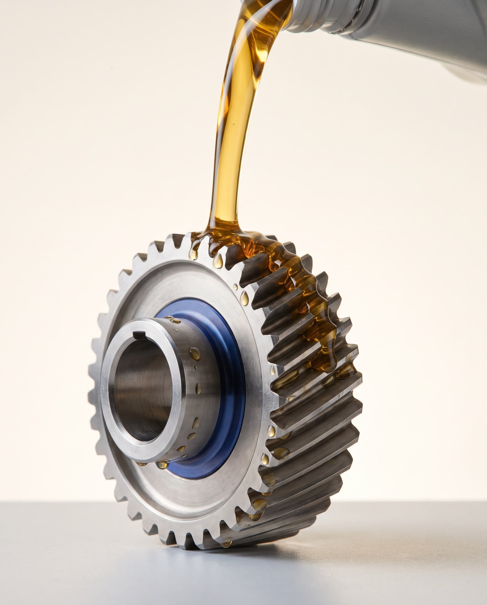 Golden synthetic oil pouring over a polished helical gear