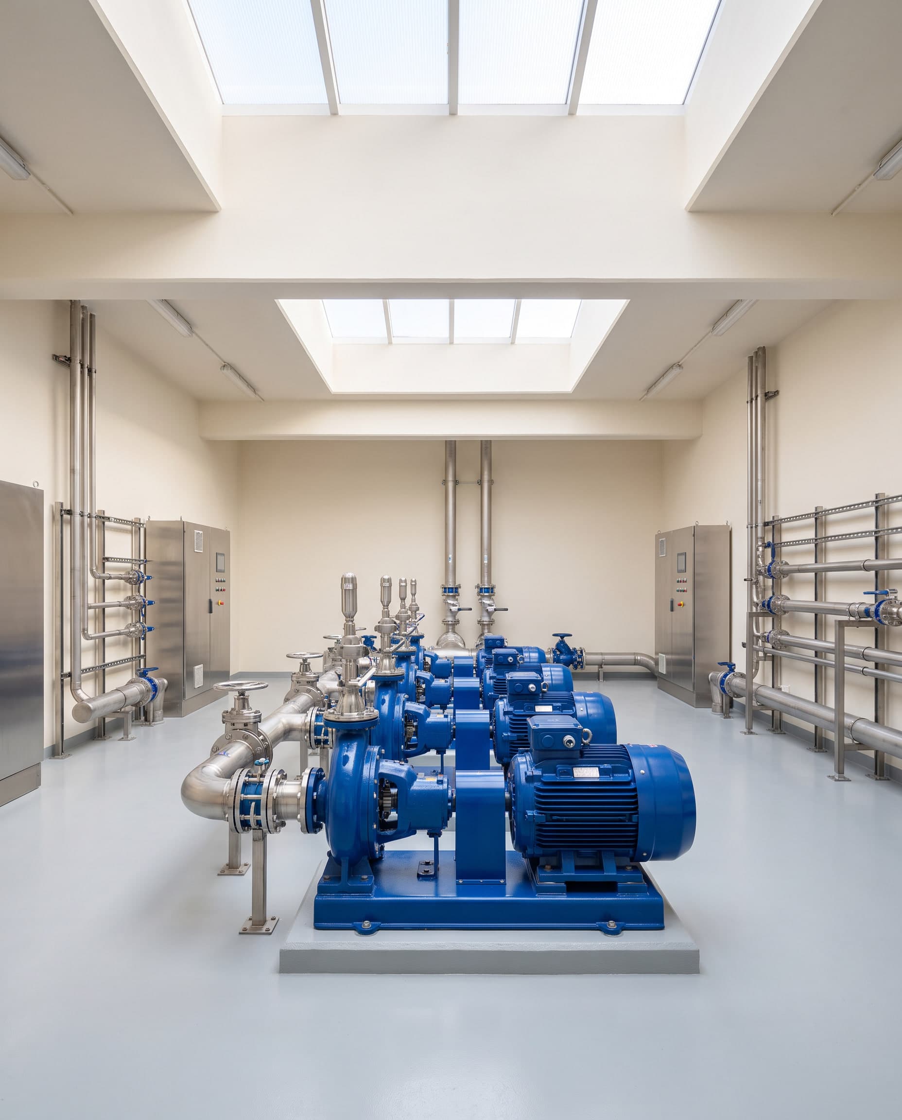 Pump room with blue centrifugal pumps and stainless manifolds