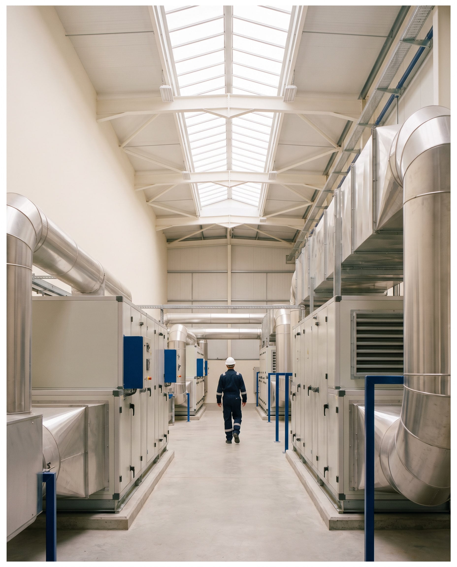 Engineer walking through a bright plant room lined with air handling units