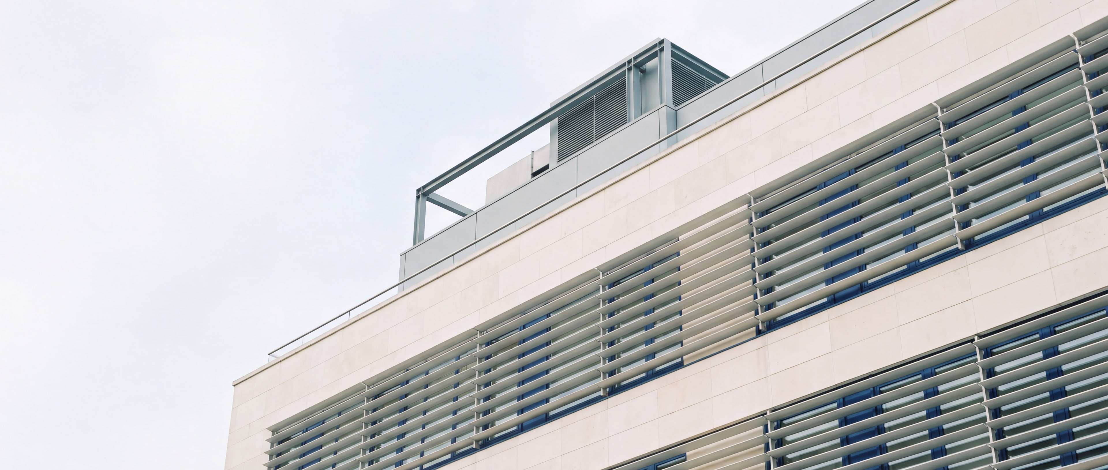 Modern commercial tower facade with aluminium louvres and rooftop plant